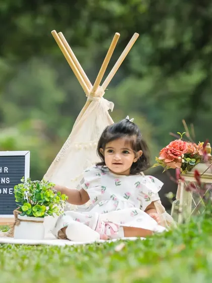 One half of a beautiful twin duo, this little girl enjoys her outdoor first birthday shoot with a teepee and sign.