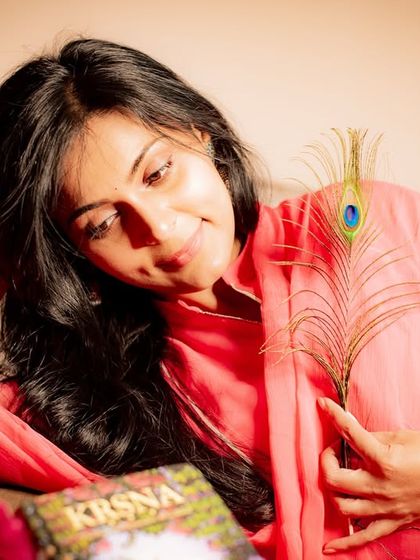 A gentle and contemplative portrait. The use of props like the book and feather adds to the narrative of the image.