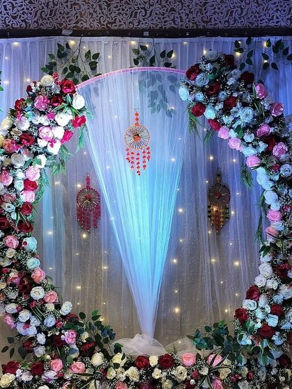 The lighting can be adjusted to change the mood of the decor. Here, blue uplighting gives the floral Roka ceremony backdrop a cool, evening-ready look.