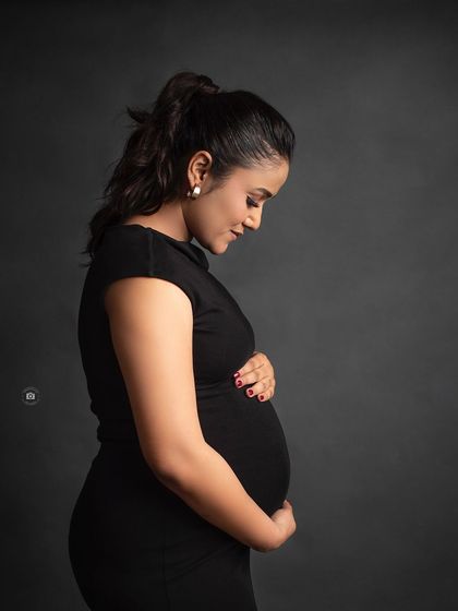 A gentle and classic black and white portrait of a mother-to-be cradling her bump, her hair tied back to create a clean and elegant look.
