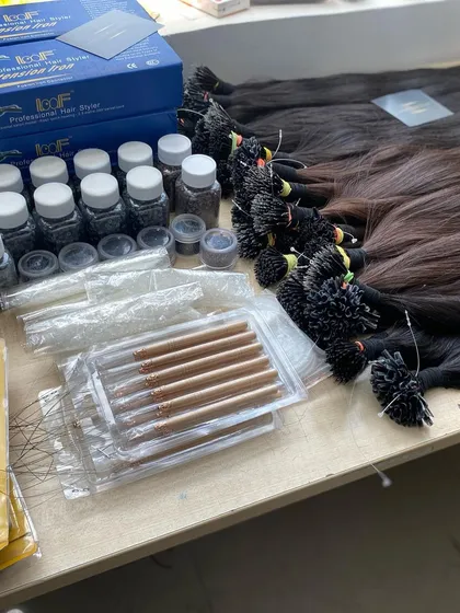 A complete set of our hair extension tools and supplies laid out on a table. We provide everything salons need, from hair bundles and tips to application tools and micro beads, all available for bulk purchase.