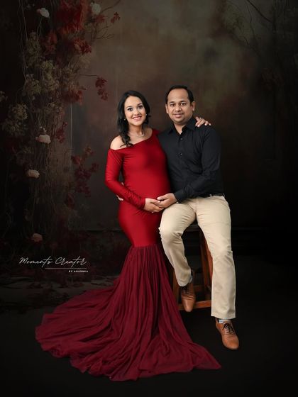 A cozy and intimate couple's portrait. The warm, earthy tones of the backdrop complement the bold red gown, creating a rich and inviting scene.
