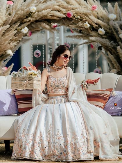 A candid shot of the bride at her Mehendi, holding a basket of flowers, looking effortlessly chic and happy.