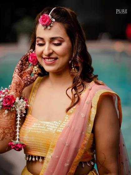 A close-up portrait of the bride from her Haldi ceremony. Her floral jewelry and radiant smile are the highlights of this beautiful shot.