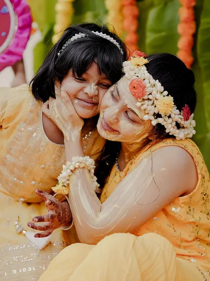 A heartwarming hug between the bride and a younger family member, both glowing with turmeric and happiness. These are the precious family moments that make a wedding so special.
