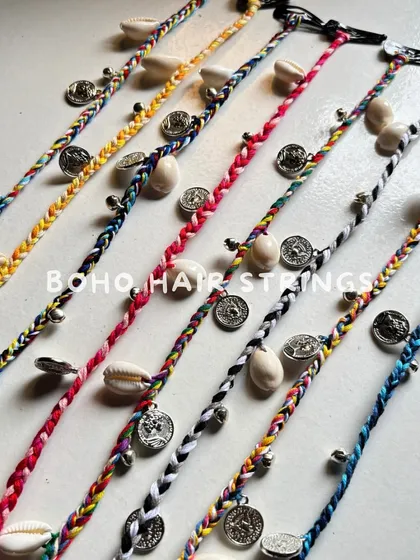 These boho hair strings are a must-have for festival season. I braid them with colorful threads and adorn them with cowrie shells and little metal coins that jingle when you move.
