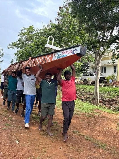 Teamwork extends beyond the water. Here, a group of participants carries a canoe together after a session, demonstrating shared responsibility.