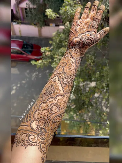 A stunning outdoor shot of Anam's Pakistani-style bridal henna, showing the full arm design in natural light.