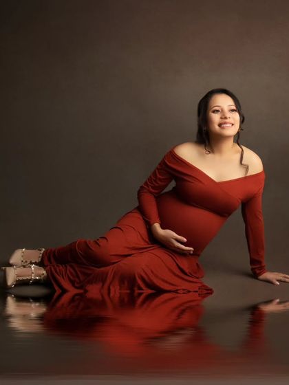 The reflection on the floor adds a beautiful, artistic dimension to this portrait of a happy mom-to-be in her orange gown.