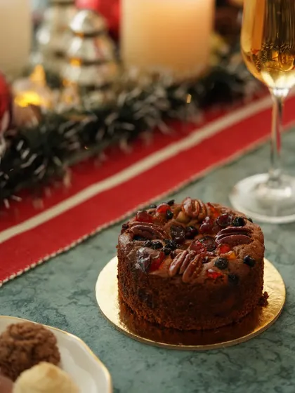 A non-alcoholic plum cake, rich with fruits and nuts, styled on a festive table for an inclusive holiday celebration.