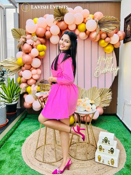 A bright and cheerful terrace party setup with pink and yellow balloons and boho elements.