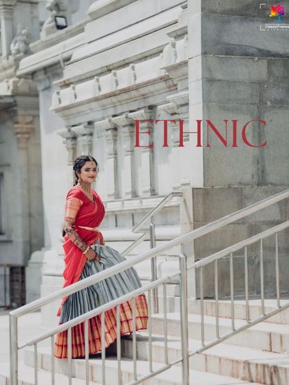 An elegant full-length portrait of the bride on a staircase, showcasing her traditional half saree. The architectural elements of the temple complement her ethnic attire.