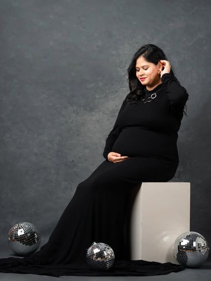 A glamorous pose with a long black dress and disco balls. This shot combines elegance with a hint of party-ready fun.