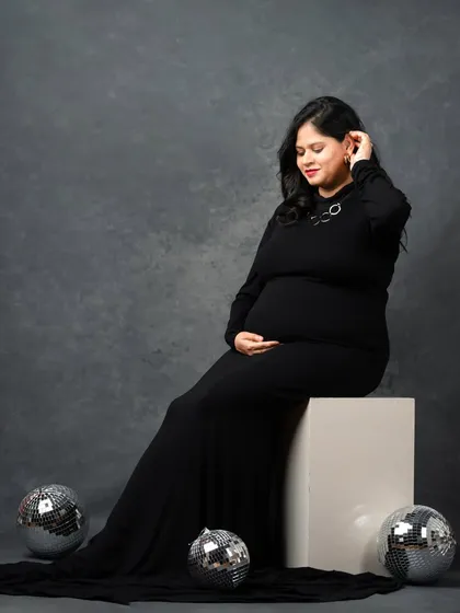 A glamorous pose with a long black dress and disco balls. This shot combines elegance with a hint of party-ready fun.