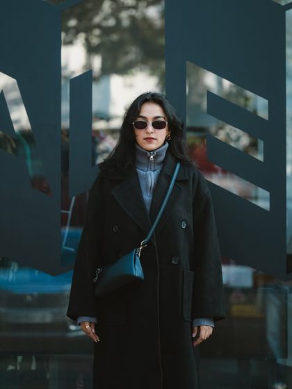 This full-body street style photo showcases the complete outfit against a modern, graphic background. The composition is clean and centered, making the model and her fashion the clear focus.
