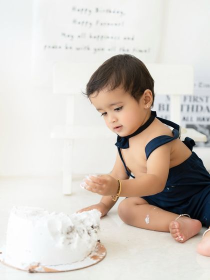 And the smashing begins. A candid shot of the baby getting his hands messy with cake, a classic and fun moment in every cake smash session.