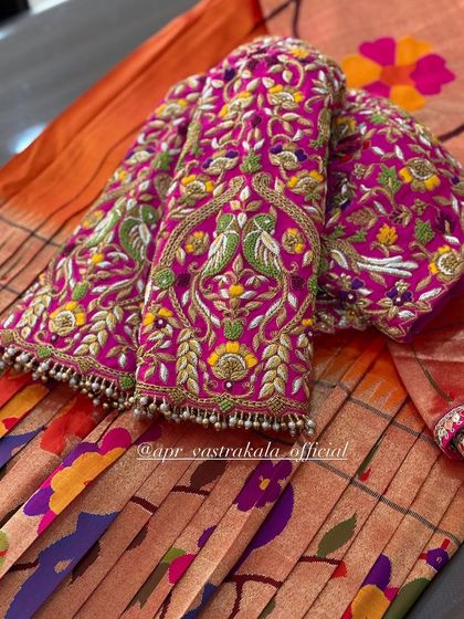A pink blouse with multi-color floral and peacock embroidery on the sleeves.