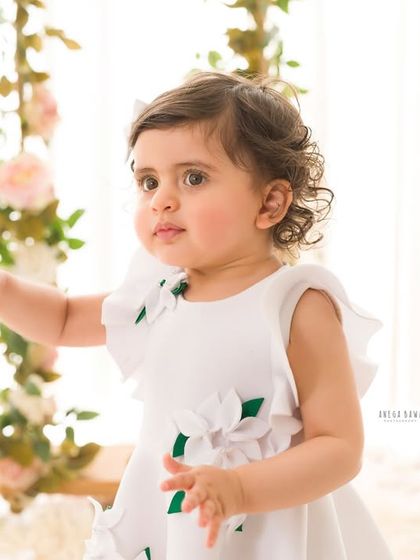A curious and innocent portrait of a little girl reaching out. The soft, natural light highlights her delicate features and curly hair.