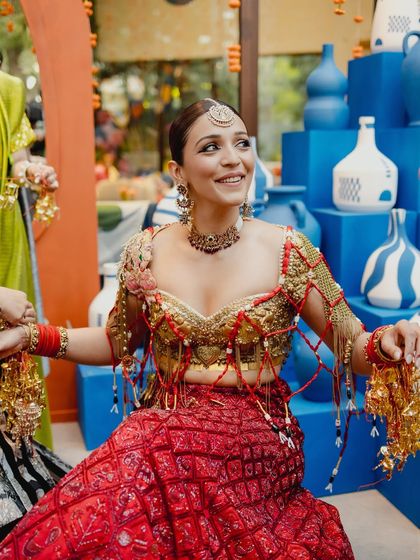 A happy, candid moment from the Mehendi ceremony. The bride's warm, bronzed glow and winged eyes stand out, even in a vibrant, festive setting.