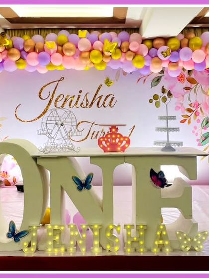 A beautiful butterfly-themed first birthday. The setup includes a 'ONE' marquee table, a pink and purple balloon arch, and large butterfly cutouts.