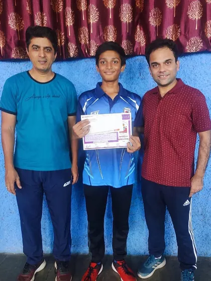 Johan Cheriparambil stands with his coaches, holding his certificate after his silver medal win at the state ranking tournament.