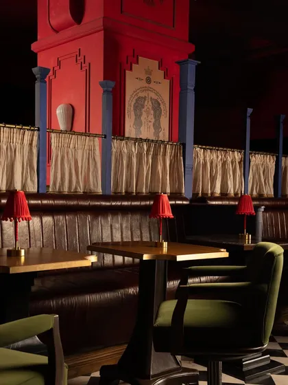 Booth seating with custom red table lamps, set against a backdrop of architectural layers and traditional motifs. Every detail is designed to contribute to the immersive, story-rich atmosphere.