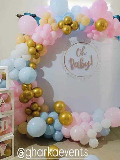 A classic "Oh Baby" gender reveal or baby shower theme. The circular white backdrop is framed by a pastel pink, blue, and gold balloon arch, with transparent 'BABY' blocks.