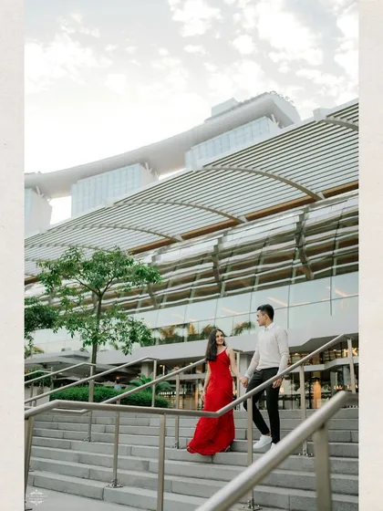 A stylish portrait of a couple on a grand staircase with Singapore's Marina Bay Sands in the background. The architecture adds a sense of scale and drama to the shot.