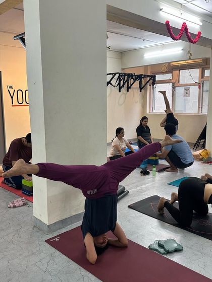 A student demonstrates an advanced split in a headstand (Hanumanasana in Sirsasana), a testament to her incredible strength, balance, and flexibility.