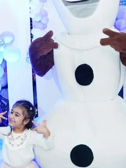 A little guest strikes a cool pose with the Olaf mascot at a 'Frozen' themed birthday party.