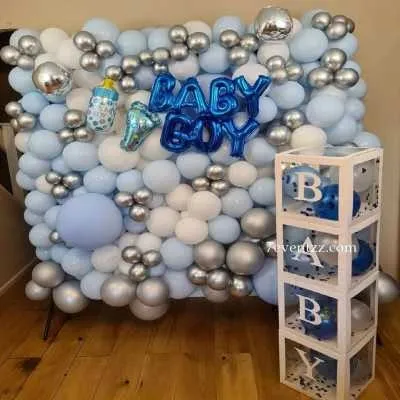 A classic "It's a Boy" announcement setup. This features a full balloon wall in shades of blue, white, and silver, with "BABY BOY" foil balloons and matching 'BABY' display boxes. This is a great option for a photo booth at a baby shower.