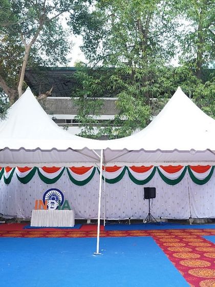 An outdoor tent setup decorated with tricolor valances for the Independence Day celebration. We provide weather-proof structures and thematic decor for outdoor government events.