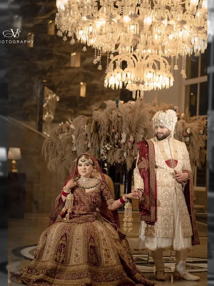 A beautiful wedding portrait of the couple holding hands, set against a backdrop of luxurious decor and a stunning chandelier.
