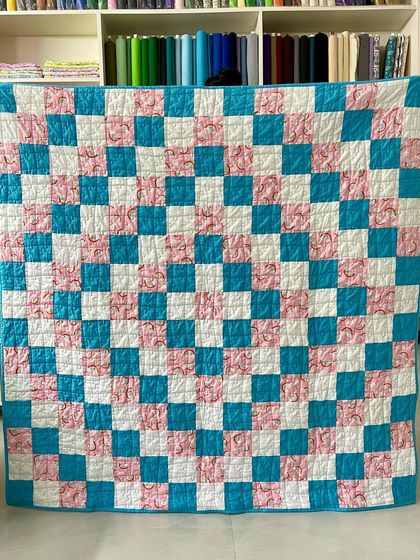 A "Trip Around the World" quilt made with cheerful pink, blue, and white fabrics.