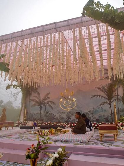 The mandap for the South Indian wedding, with a backdrop of hand-painted palm trees, a ceiling of hanging tuberoses, and a golden Ganesha motif, all creating a serene and spiritual atmosphere.