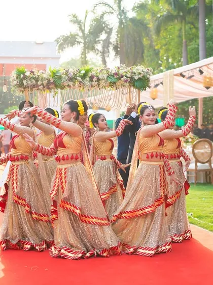 A team of my professional dancers, dressed in coordinated traditional outfits, performs a graceful welcome dance along a red carpet. This sets a festive and elegant tone for the guests and the main procession.