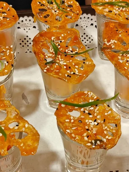 Crispy lotus stem chips served in individual shot glasses. This creative appetizer is a crowd-pleaser, offering a unique texture and savory taste.