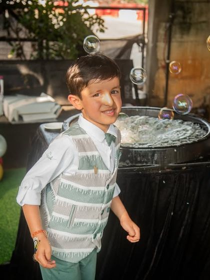 A candid shot of the birthday boy enjoying the bubble machine. The soap bubble on his nose adds a touch of humor and charm to this fun photo.