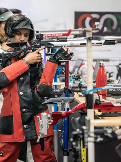 A young shooter carefully raises her rifle, preparing for her shot. This image captures the foundational techniques we instill in our athletes from day one.