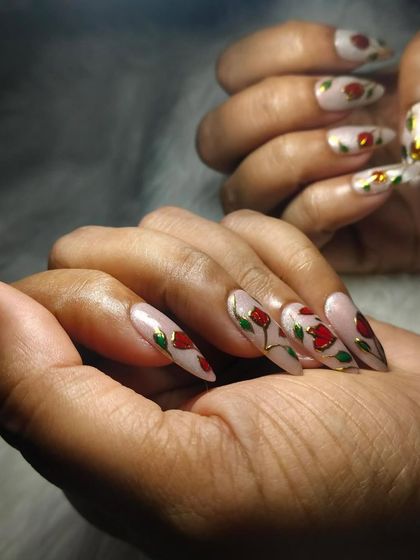 Another view of the beautiful hand-painted rose nail art. The soft, shimmery base makes the red and gold details pop.