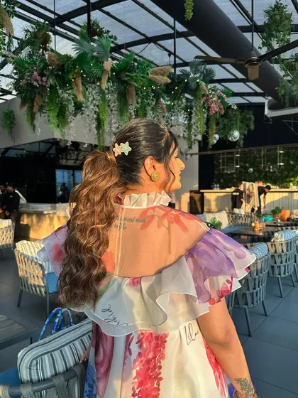 A voluminous curly ponytail for a baby shower. The cute star-shaped clips add a sweet, personal touch to this happy and celebratory hairstyle.