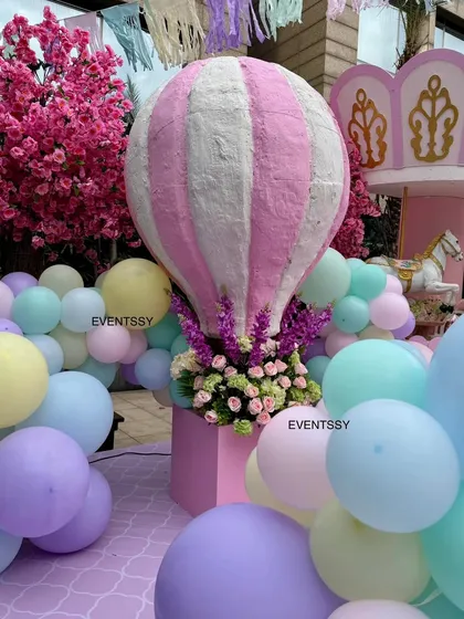 A large hot air balloon prop serves as a beautiful centerpiece, emerging from a sea of pastel balloons.