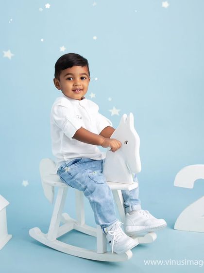 Giddy up, it's my second birthday. This playful shot captures the birthday boy on a white rocking horse, a fun prop to use during toddler milestone sessions.