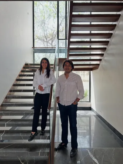 The co-founders on the modern, light-filled staircase of the 'House of Passages' project. The design features open risers and a large window that floods the space with natural light.