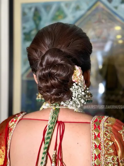 A classic bridal bun decorated with a gajra of fresh flowers. This timeless style is perfect for a traditional wedding ceremony.
