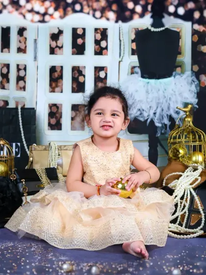 A happy, candid moment from the chic photoshoot, with the baby girl smiling and playing with a golden prop.