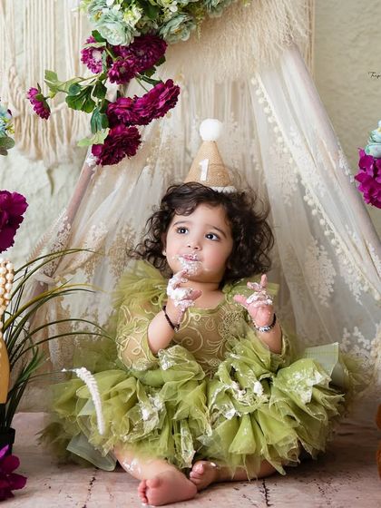 A little bit of cake, a whole lot of fun! This sweet girl is enjoying her first taste of birthday cake in a lovely green and purple boho-chic setup.