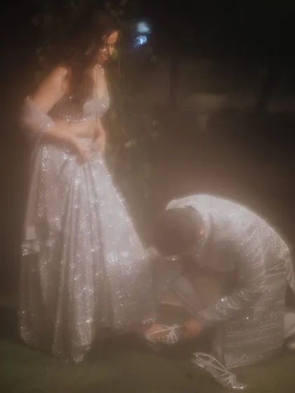 A modern-day fairytale moment. The groom helps his bride with her shoe, a gesture of love and care captured in a dreamy, soft light.