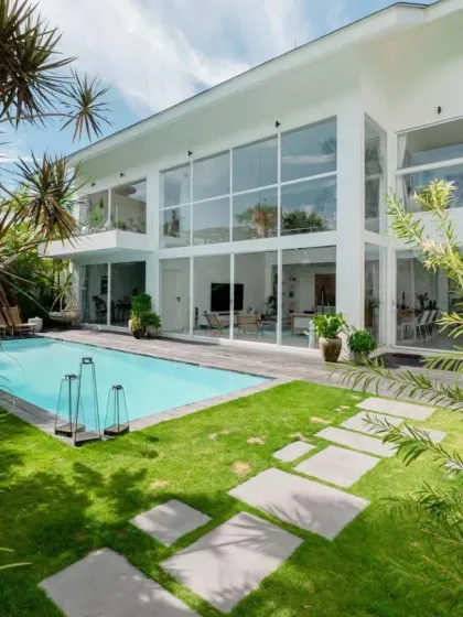 This modern villa features floor-to-ceiling windows that look out onto a tropical paradise. I used a combination of lush lawns, stone pavers, and mature palm trees to create a luxurious, resort-like feel right at home.