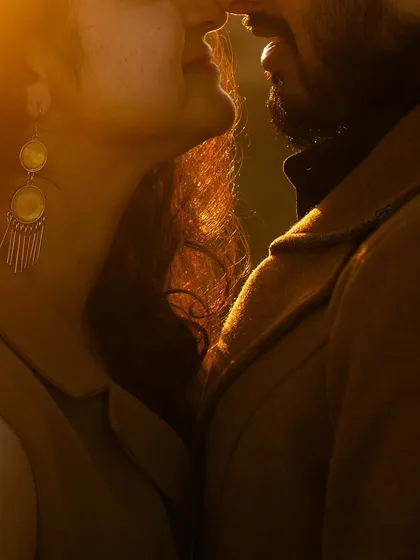 A close-up silhouette of the couple against the warm glow of the setting sun. The golden light beautifully rims their profiles, creating a dreamy and romantic mood.